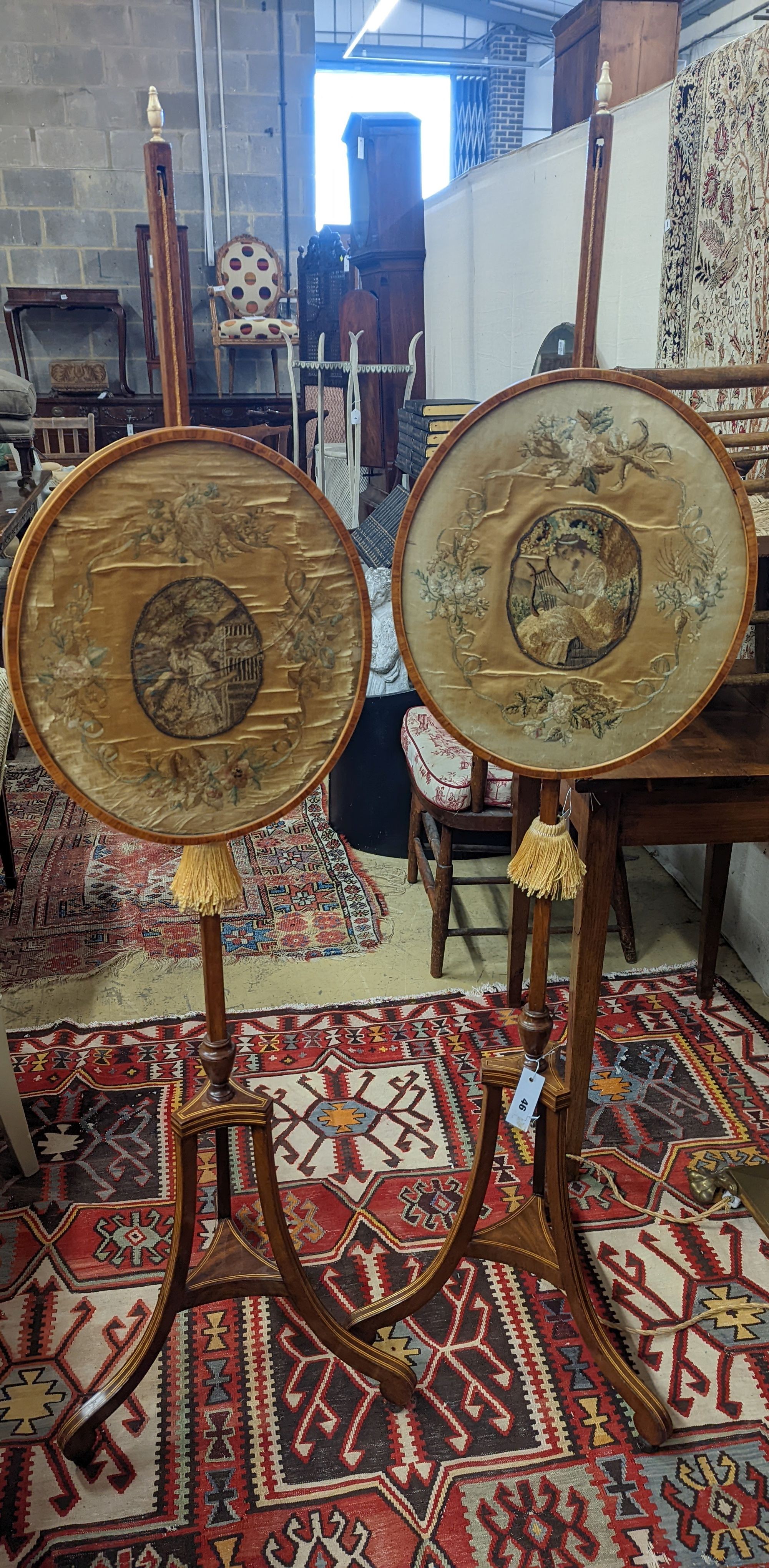 A pair of 19th century mahogany pole screens, with oval silkwork banners, height 148cm